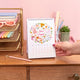 Hand holding a calendar on a desk with stationery items in the background