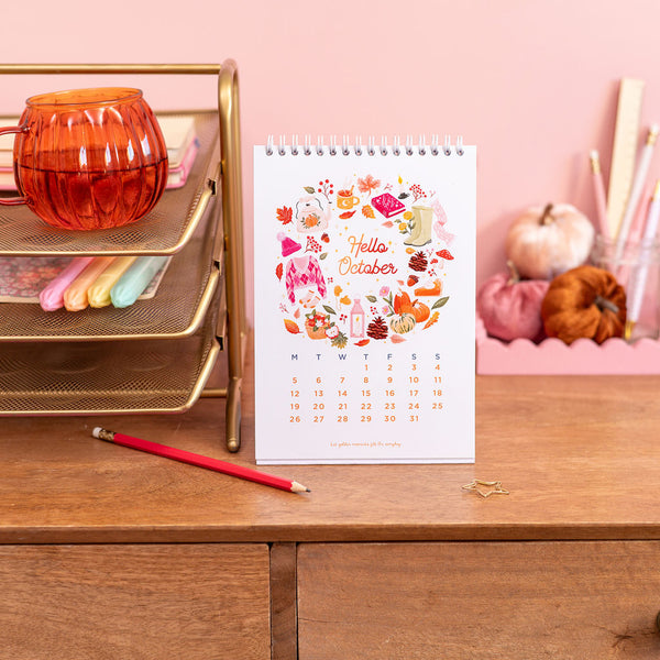 Calendar with 'Hello October' design on a desk with stationery items